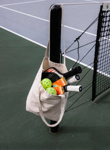 Tote bag with Sunii Energy Gum, tennis paddles, and balls on a tennis court, promoting hassle-free energy with precisely portioned caffeine boost