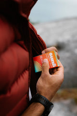 Hand placing Sunii Energy Gum into a jacket pocket, showcasing its convenient size for easy consumption on the go